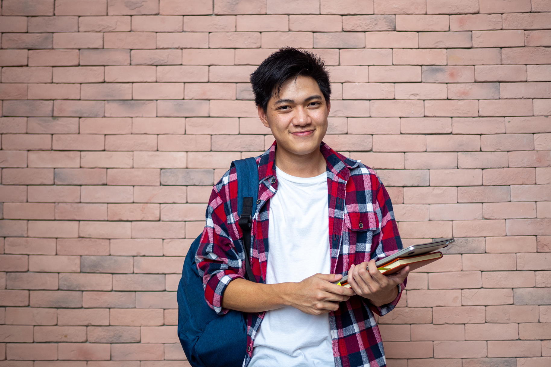 Asian Male Student Standing Next to a Brick Wall